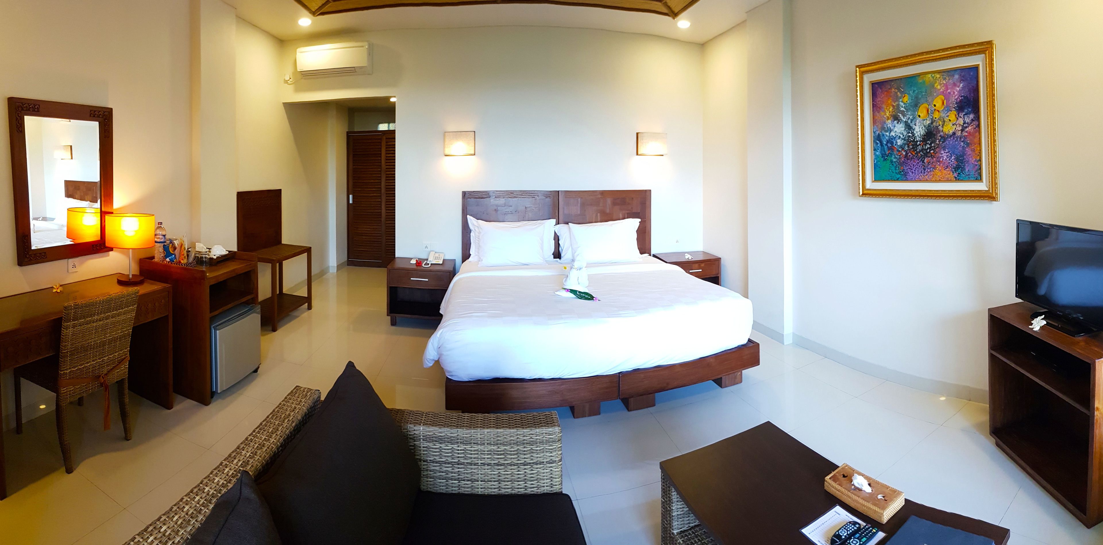 A hotel room with a large bed, a desk with a chair, a television, and a painting on the wall.