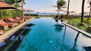 Relax by the serene pool surrounded by lounge chairs and umbrellas, with a view of the ocean and distant islands.