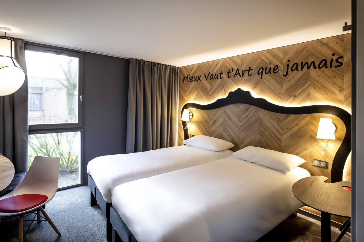 Une chambre d’hôtel avec deux lits, un coin repas et une vue sur l’extérieur.