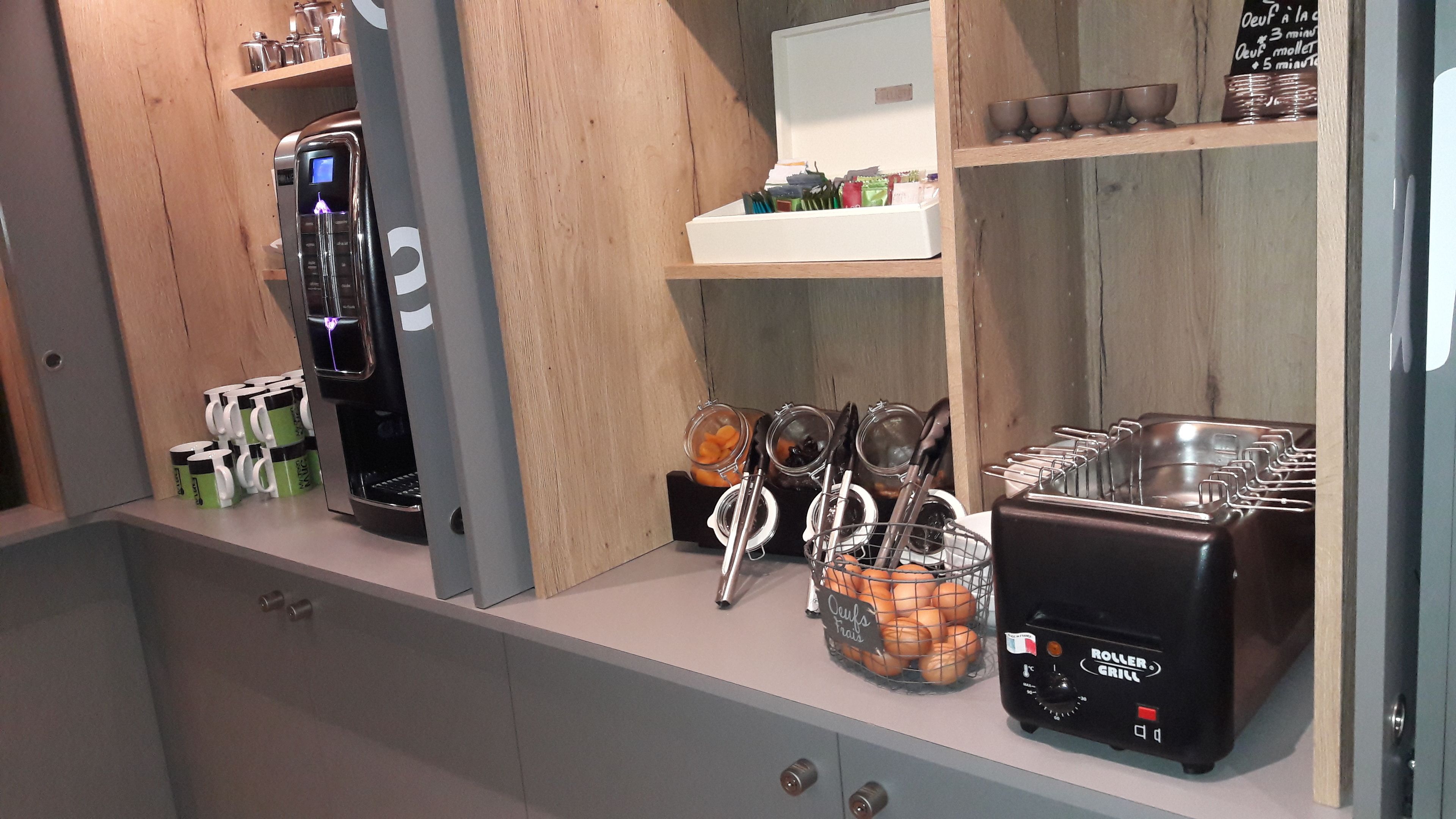 A kitchenette with a coffee machine, a toaster, and a bowl of fruit.