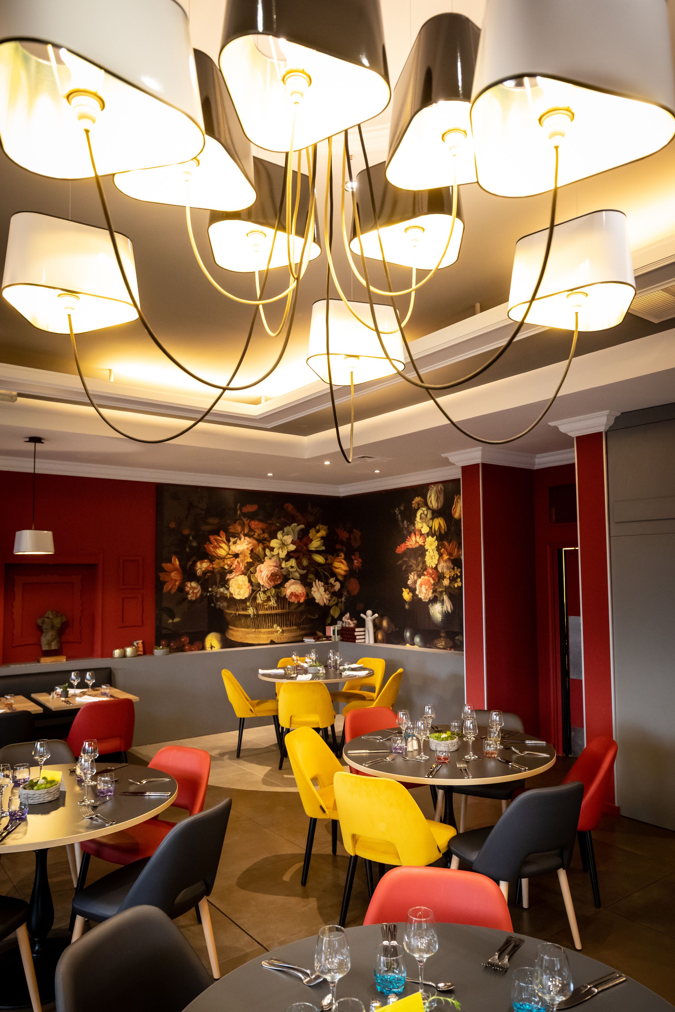 A modern dining area with round tables, colorful chairs, and a chandelier.