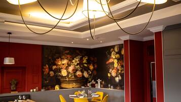 A modern dining area with round tables, colorful chairs, and a chandelier.