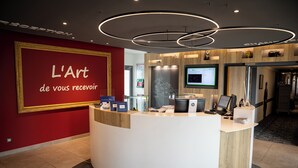 Een receptiegedeelte met een rode muur, een receptiebalie, een wandgemonteerde televisie en een houten accentmuur.