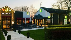 Hotel met terras, een tuin en een bord waarop een uitverkoop aangegeven staat.