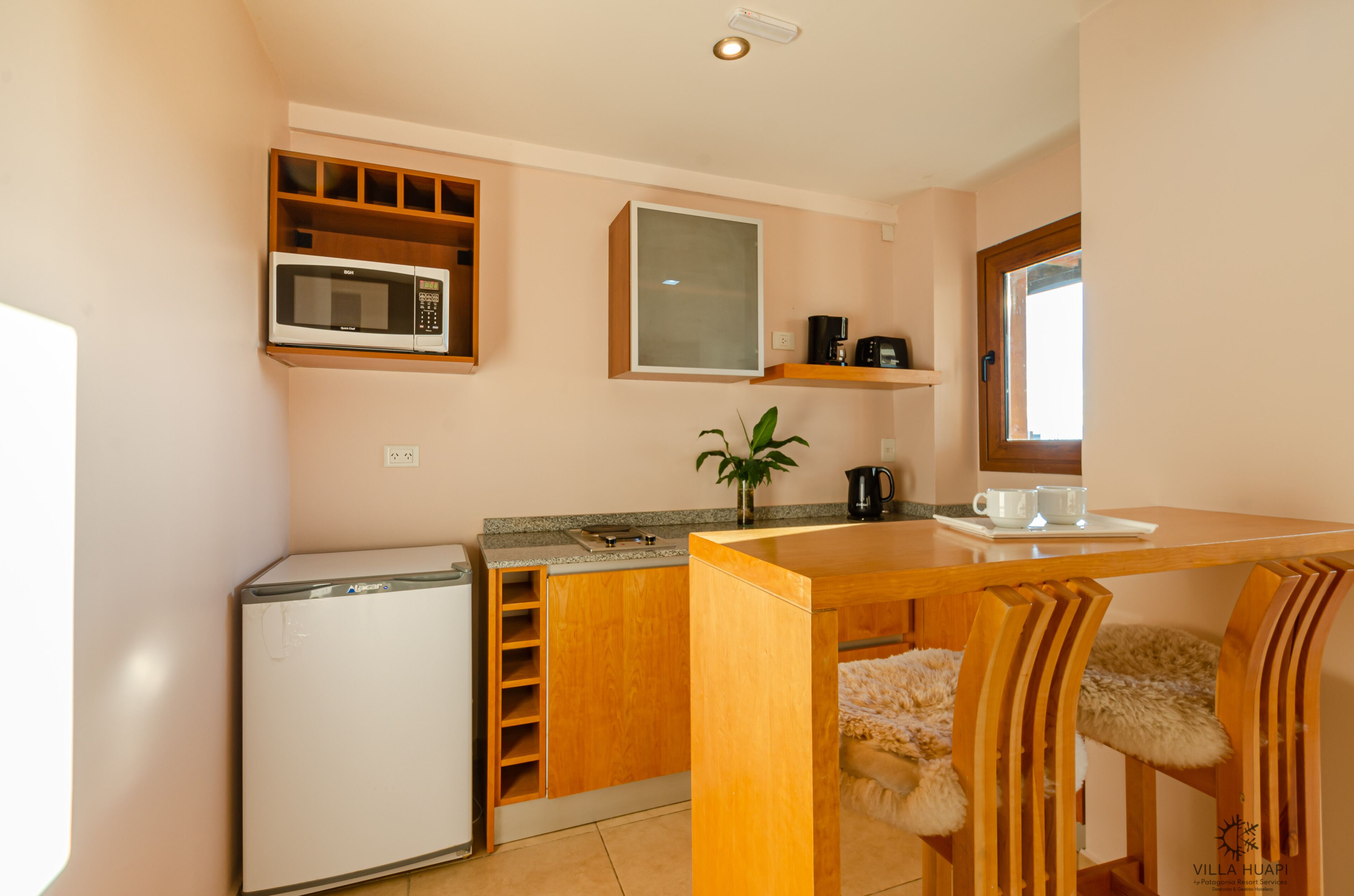 Una cocina compacta con microondas, cafetera y refrigerador pequeño.