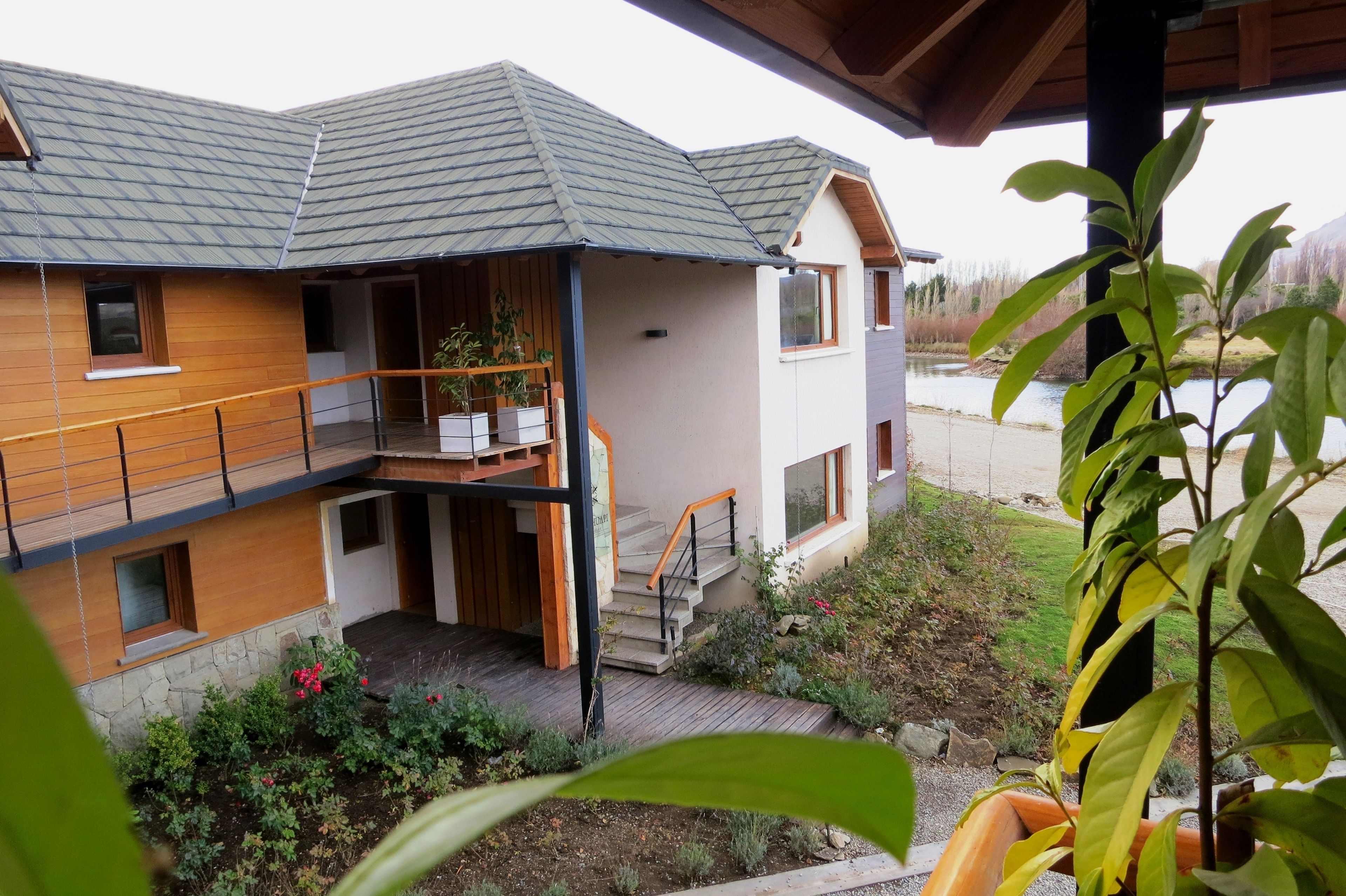 A two-story house with a wooden exterior, a balcony, and a stone foundation.