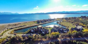 An aerial view of a residential area with houses, a lake, and mountains in the background. - Villa Huapi (Dina Huapi)