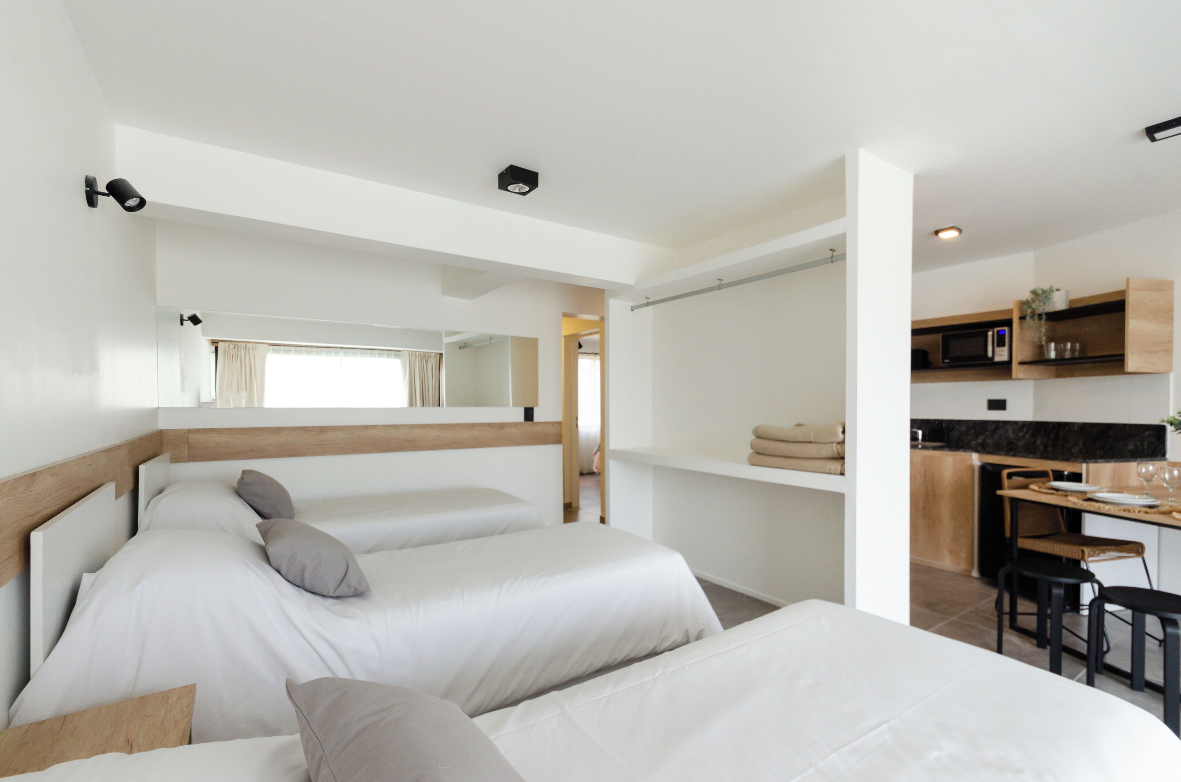 Quarto de hotel moderno com duas camas, uma kitchenette e um espaço de refeições.