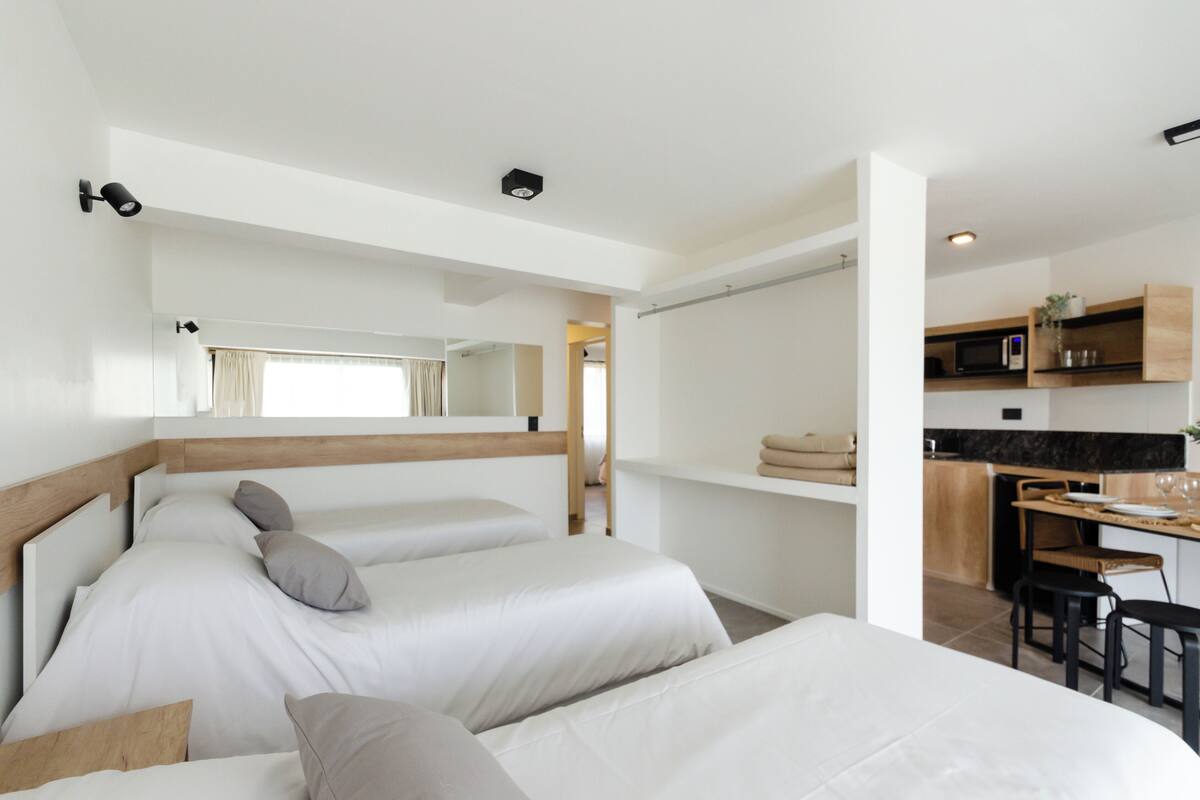 Ein modernes Hotelzimmer mit zwei Betten, einer kleinen Küchenzeile und einem Essbereich.