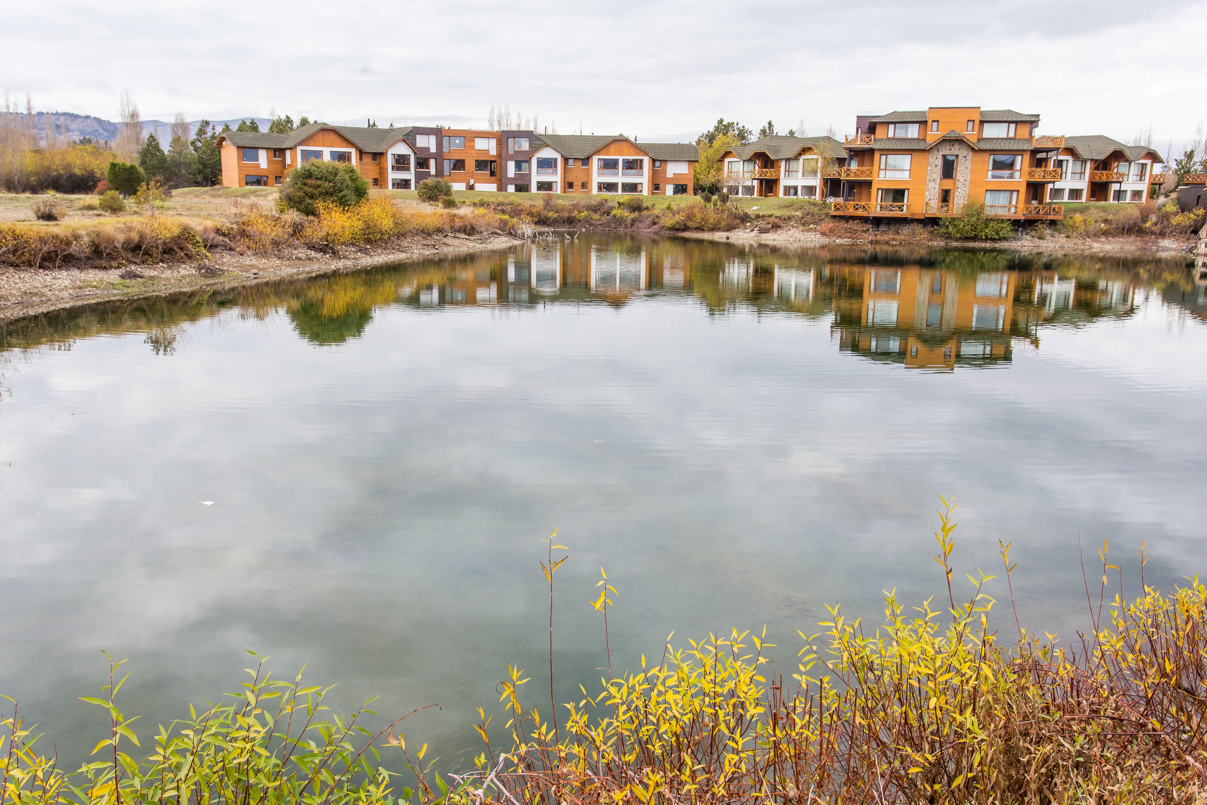 A row of modern multi-story buildings with a calm lake in the foreground.