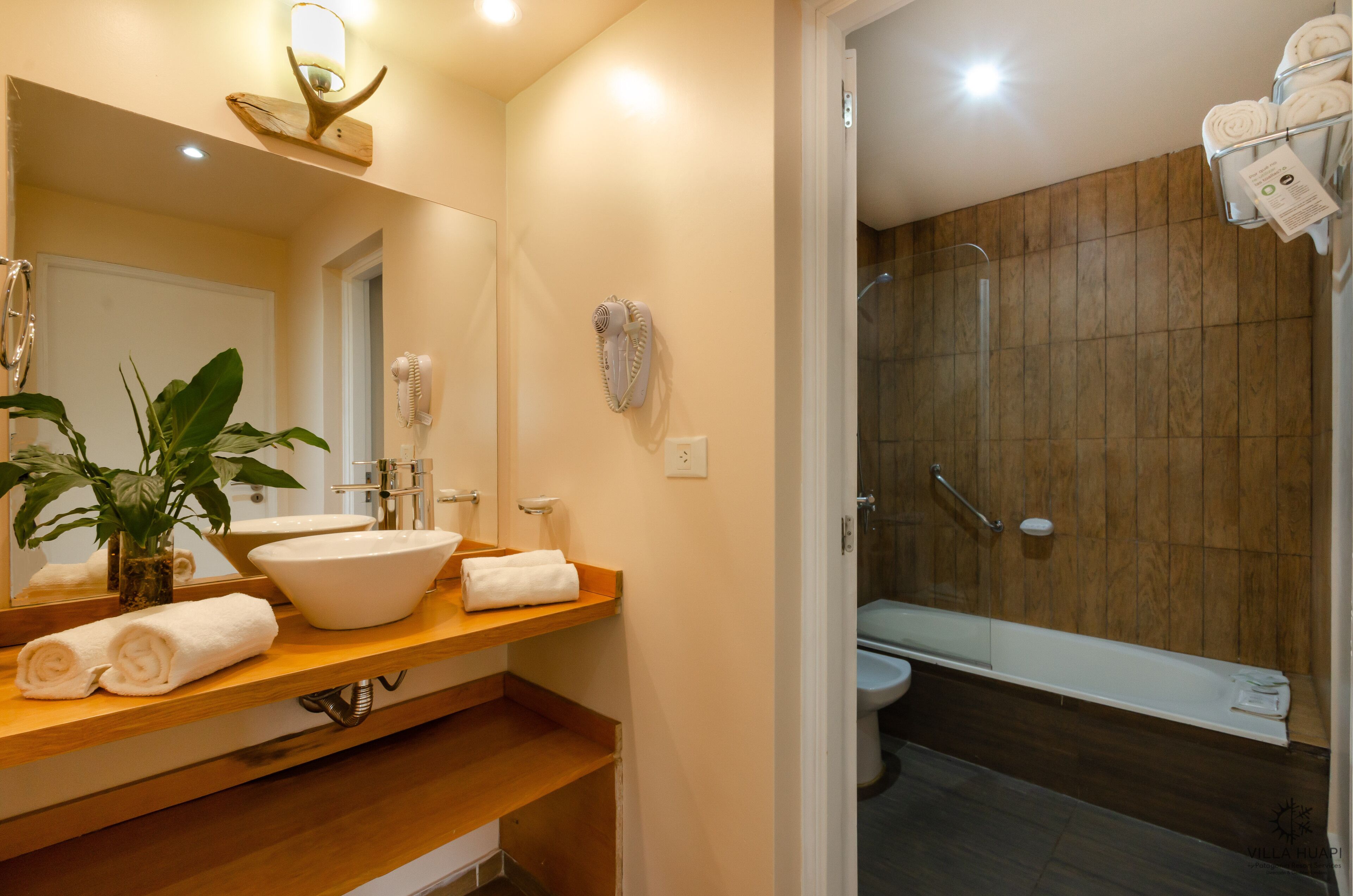 A modern bathroom with a wooden vanity, a large mirror, a sink, and a shower area.