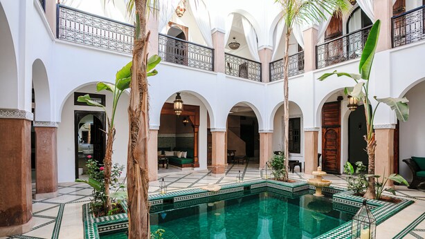 Une cour avec une piscine, des arcades et un balcon.