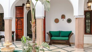 Une cour avec une piscine, une porte en bois, un canapé vert et un décor traditionnel.