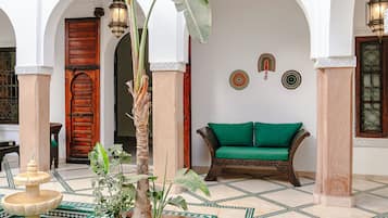 Une cour avec une piscine, une porte en bois, un canapé vert et un décor traditionnel.