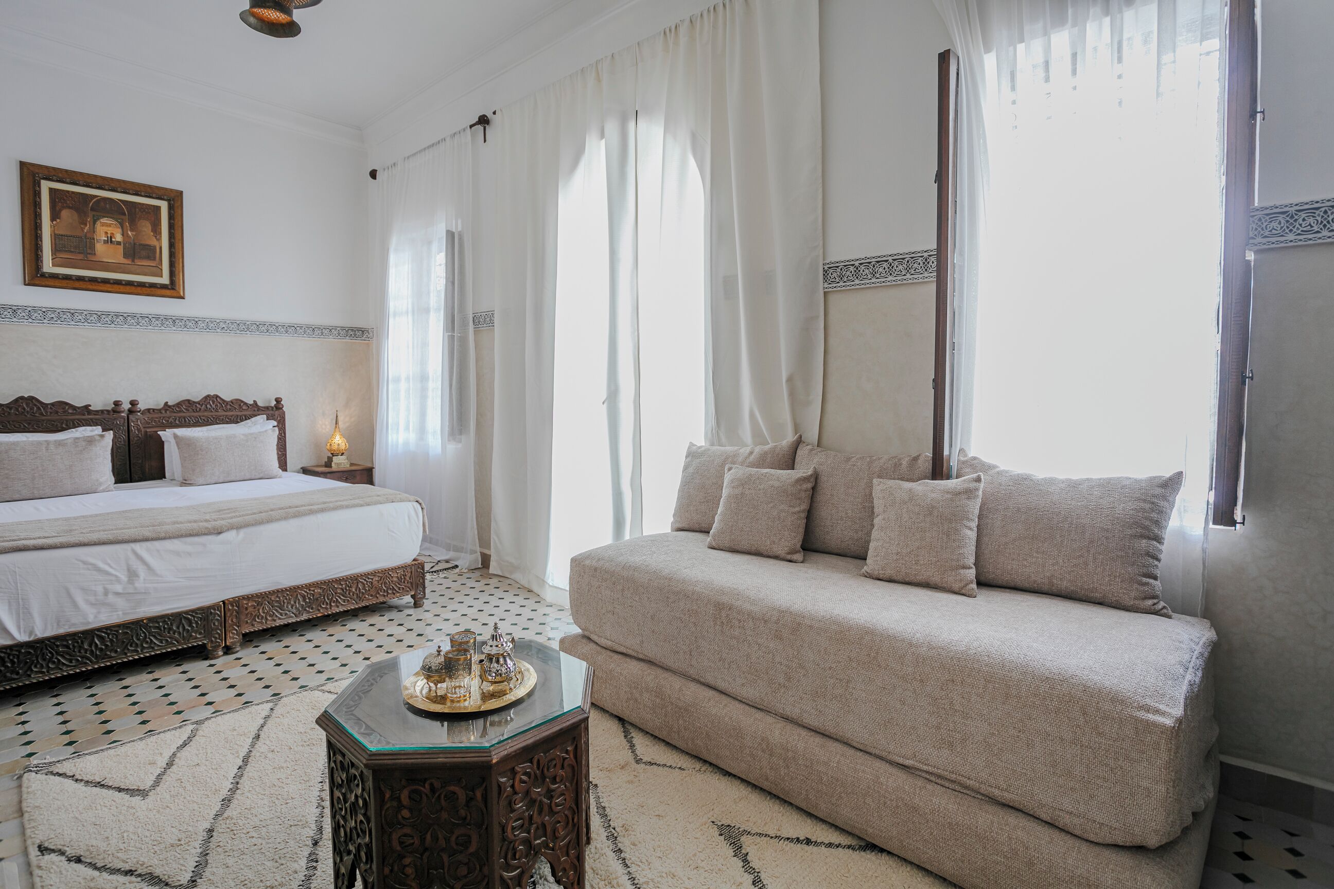 A bedroom with a bed, a sofa, a nightstand, and a decorative tray.