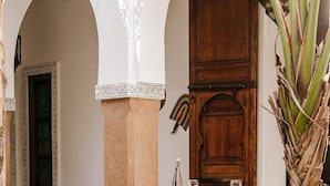 Un espace de restauration en plein air avec une table dressée pour deux personnes, entouré d’arcades et doté d’un sol à motifs.