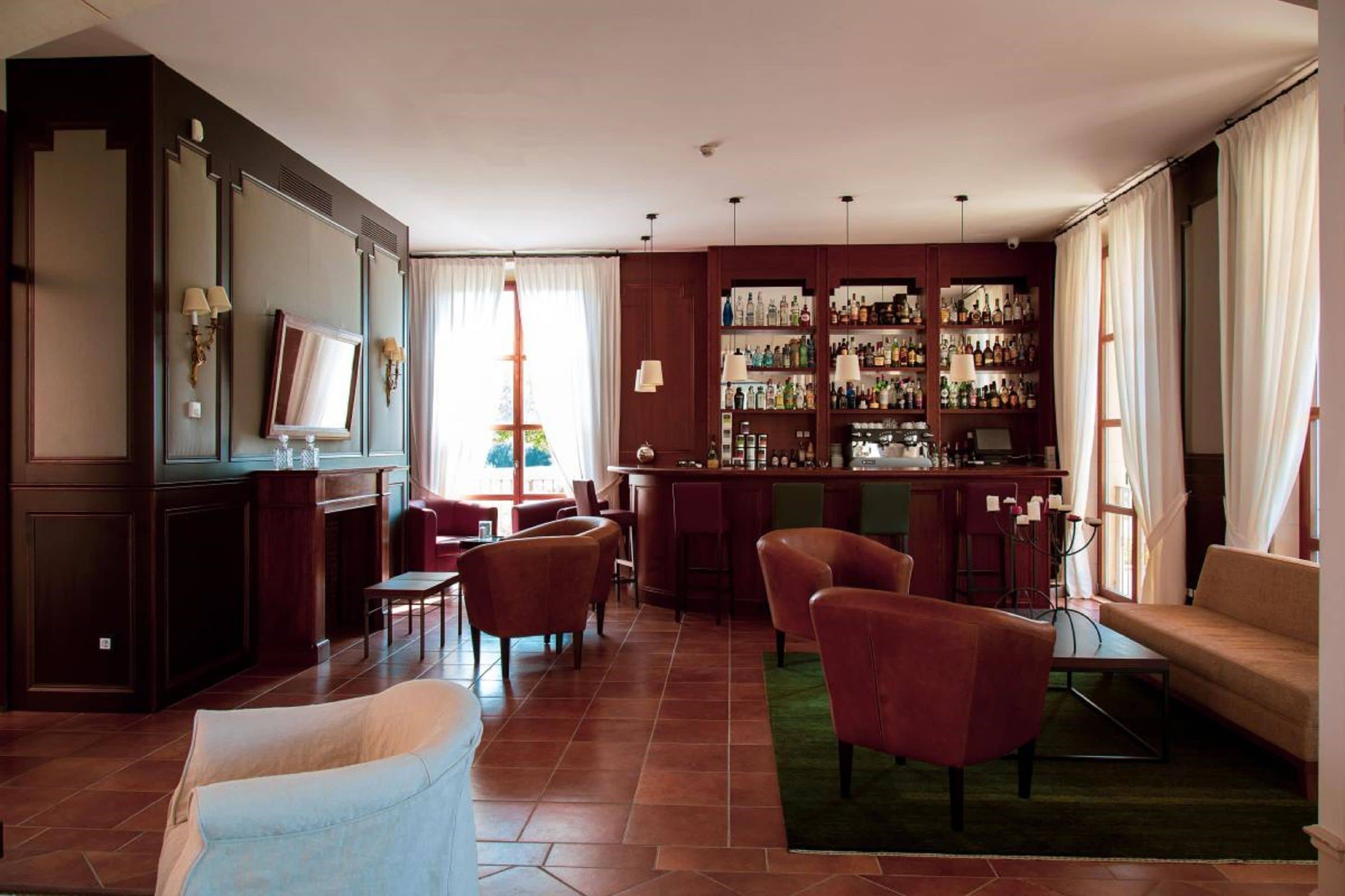 Habitación de hotel con zona de bar, asientos y televisor.