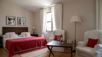 A hotel room with a bed, a chair, a table, and a lamp.