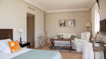 Une chambre d’hôtel comprenant un lit, un bureau, une chaise, un canapé et deux tableaux encadrés accrochés au mur.
