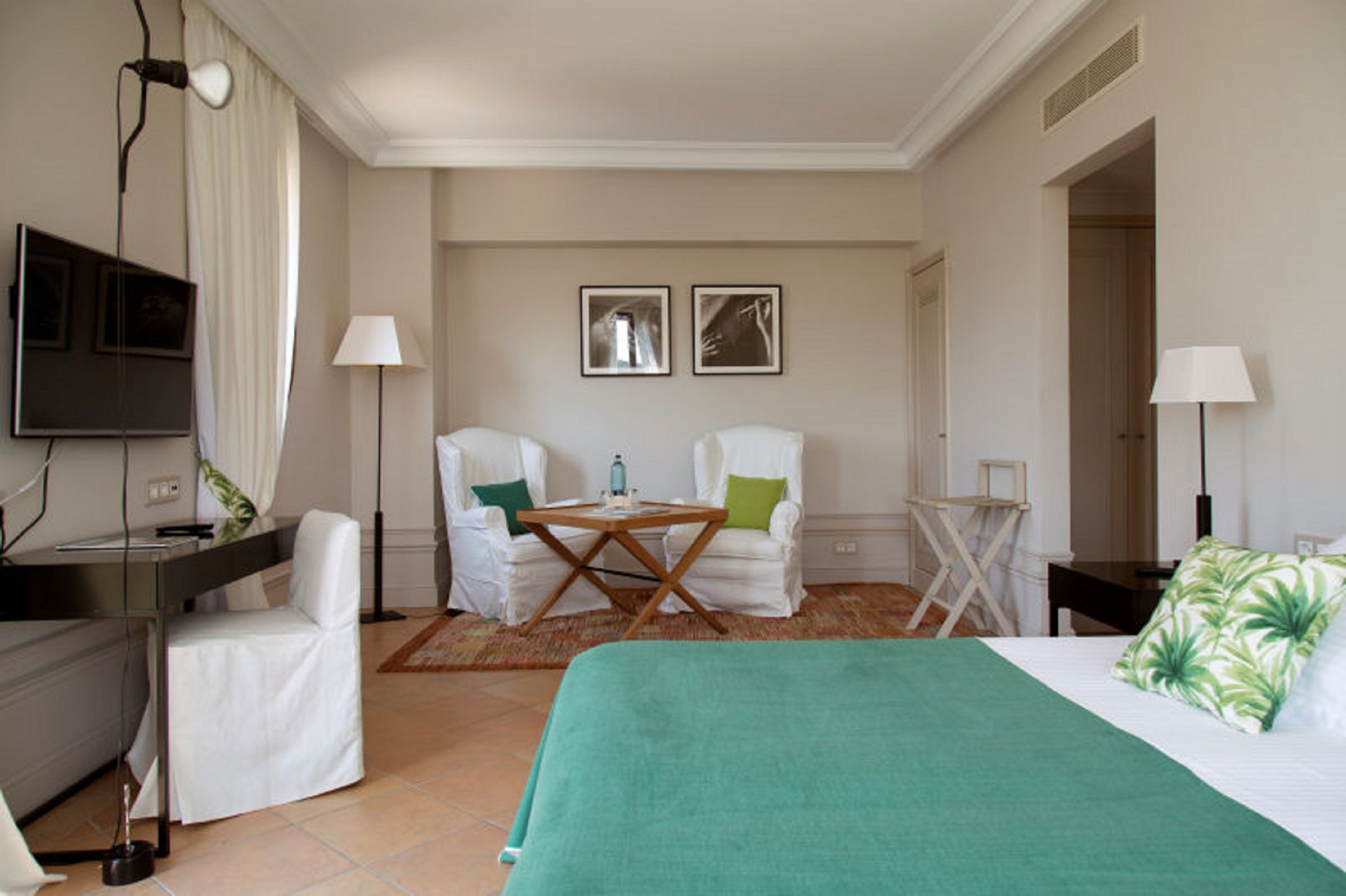 Een hotelkamer met een bed, een bureau, twee stoelen, een tafel en een televisie.