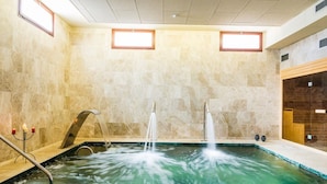Un área de spa con un jacuzzi, dos chorros de agua y un banco de madera.