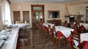 A dining area with multiple tables and chairs, a buffet setup, and a television on the wall. - Villa Armin (Rovinj)