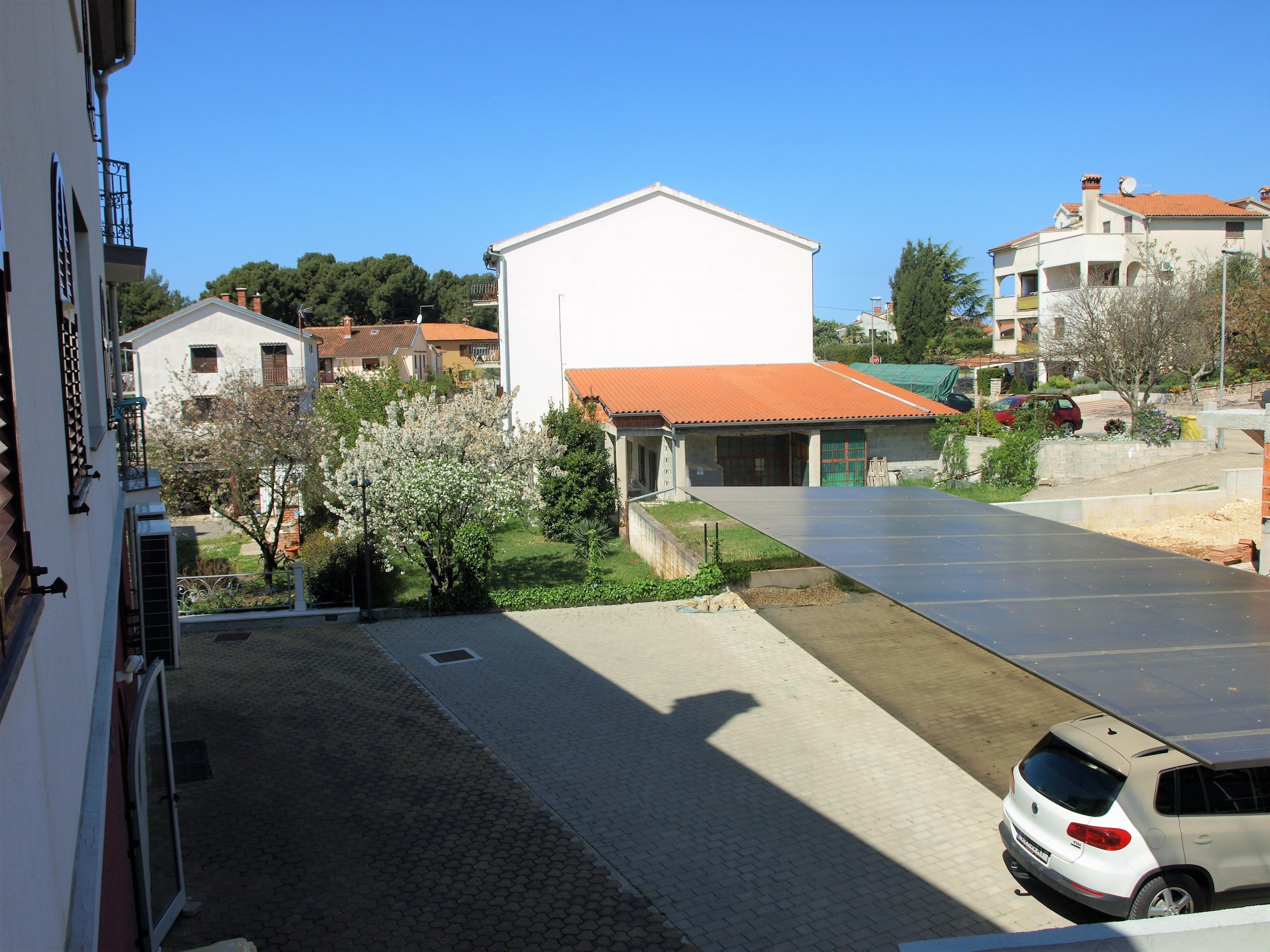 Eine Wohnstraße mit einem weißen Gebäude, geparkten Autos und blauem Himmel.