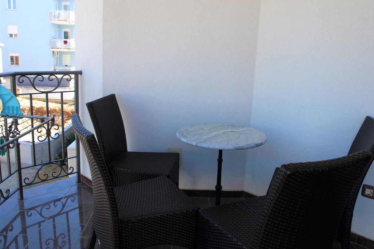 Ein kleiner Balkon mit Korbstühlen und einem Marmortisch.