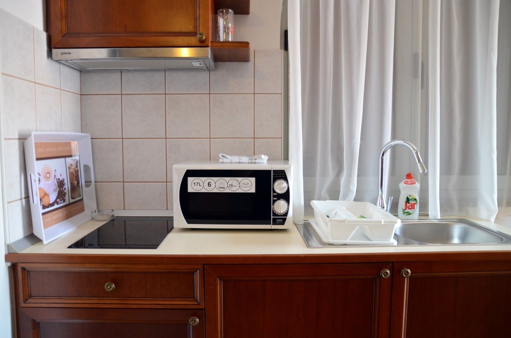 A kitchen with a microwave, toaster, sink, and a dish rack.