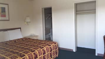 Une chambre d’hôtel avec un grand lit, une table de chevet avec une lampe, un téléphone et une armoire.