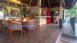 Ein Restaurant mit Holzkufen und Fliesenboden, eine Barbereich mit einem roten Stuhl und ein Gemälde einer Straßenszene an der Wand.