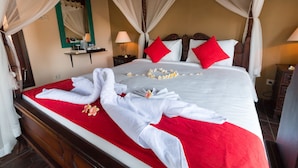 Ein ordentlich gemachstes Bett mit weißen Leinen, roten Kissen und einer roten Tagesdecke.