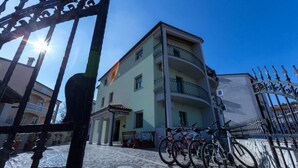 Ein Gebäude mit Balkon, Tor und abgestellten Fahrrädern vor der Fassade.