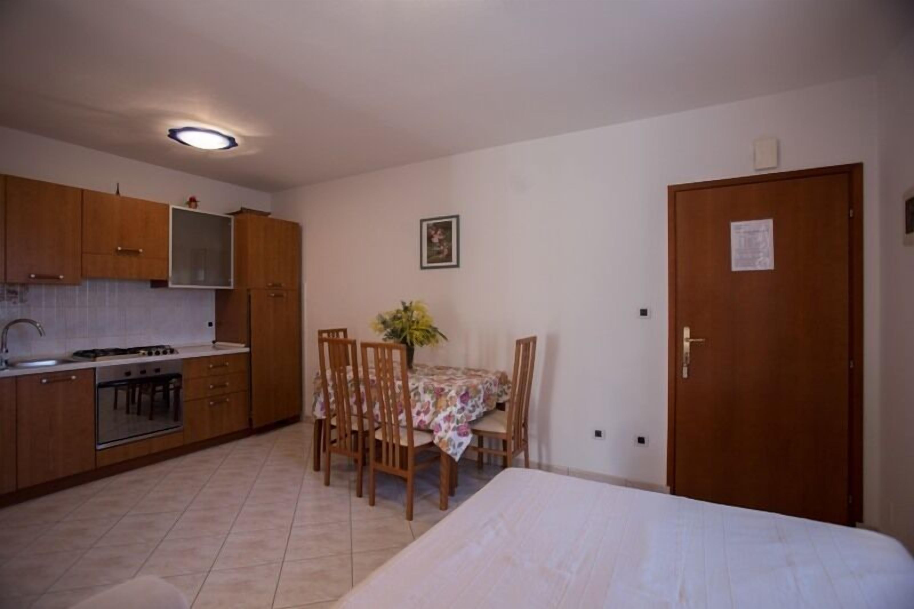 A compact kitchen with wooden cabinets, a gas stove, and a dining area with a table and chairs.