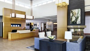 A modern hotel lobby with a reception desk, seating area, and a fireplace. - Hyatt Place New York/Yonkers (Yonkers)