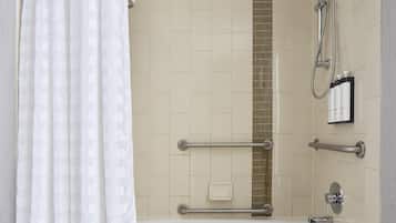 Un baño moderno con bañera, ducha y barras de apoyo.