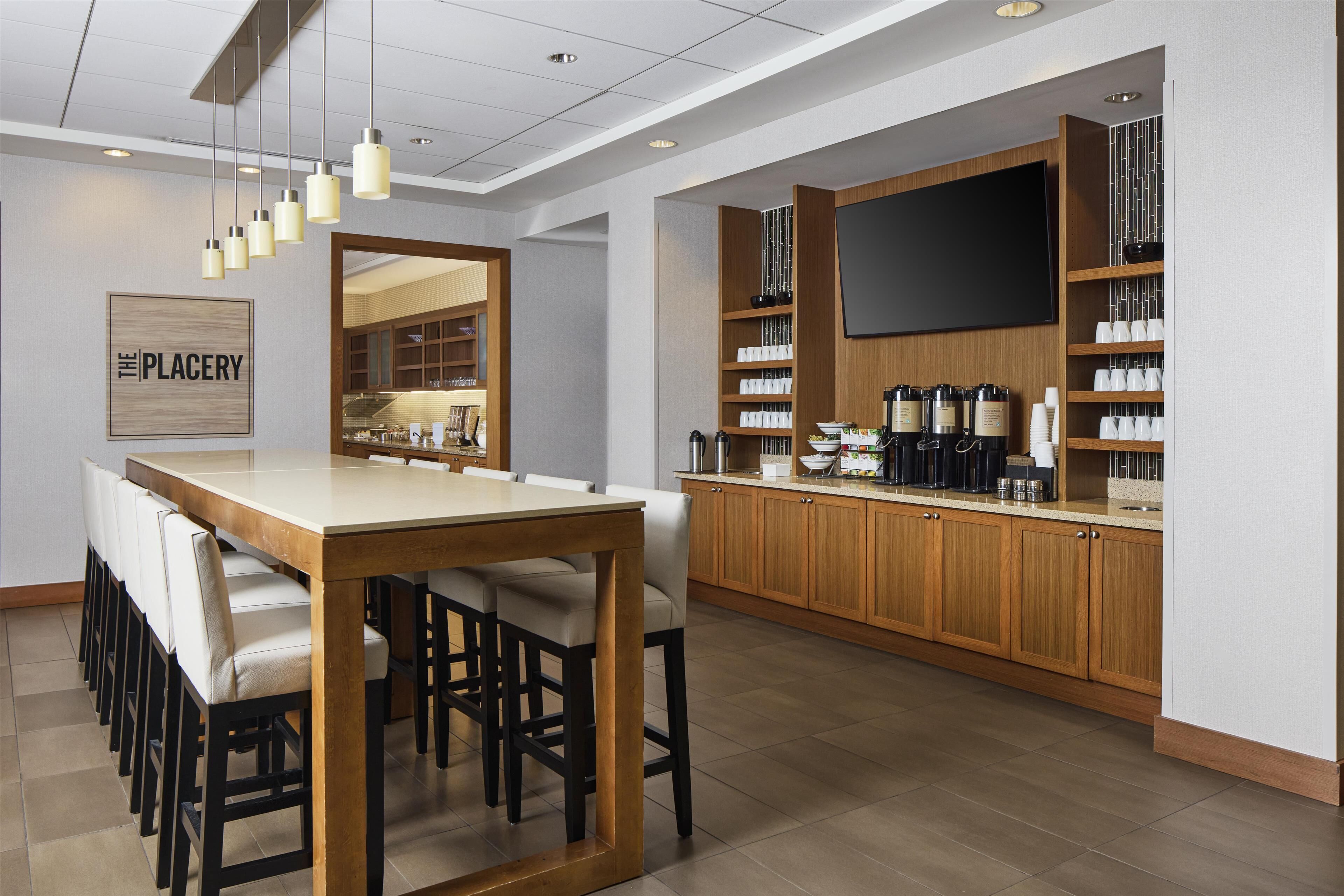 A modern kitchen with a wooden island, bar stools, and a flat-screen TV mounted above the counter.