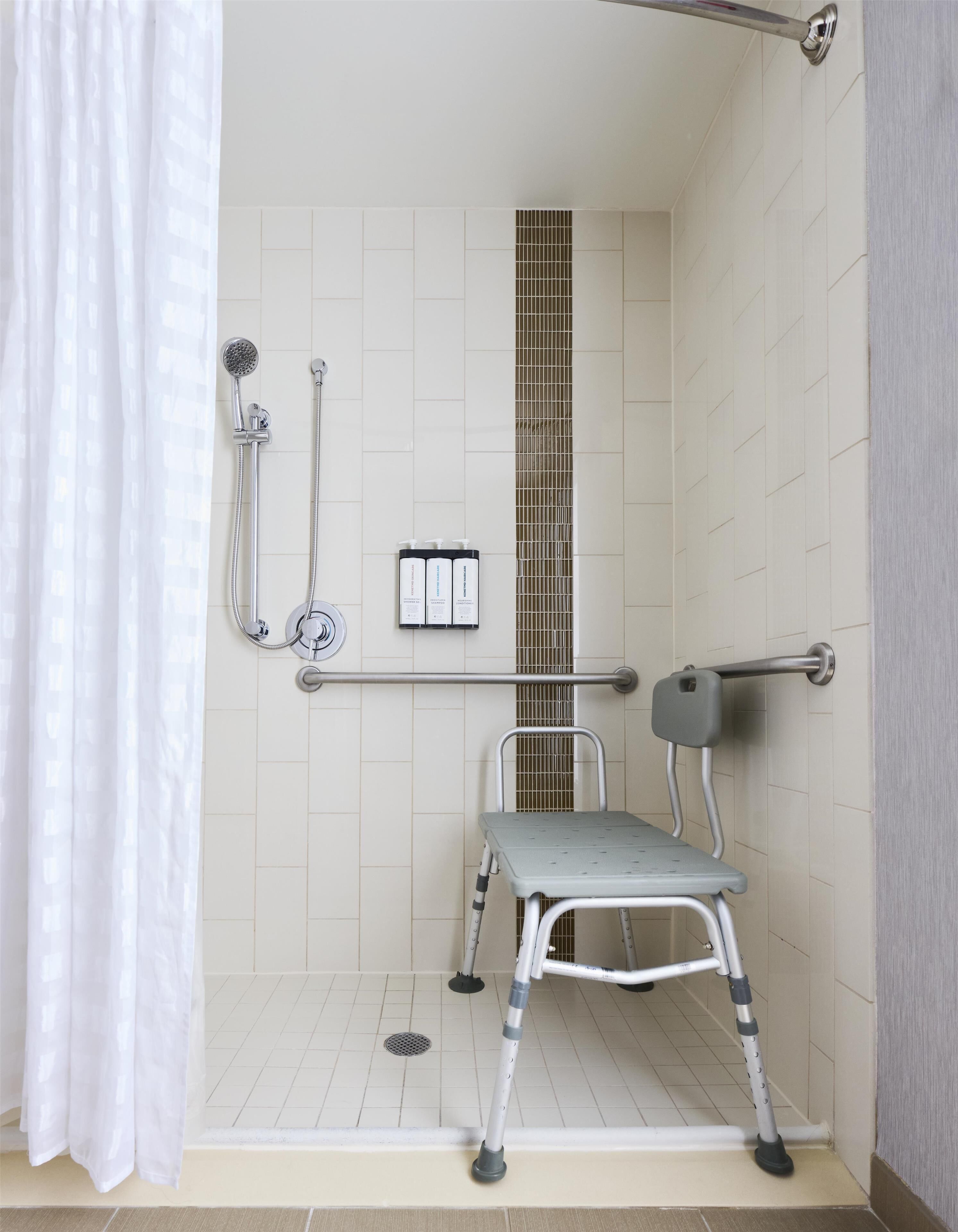 Ein barrierefreies Duschbad mit Haltegriff, Duschkopf und Handbrause.