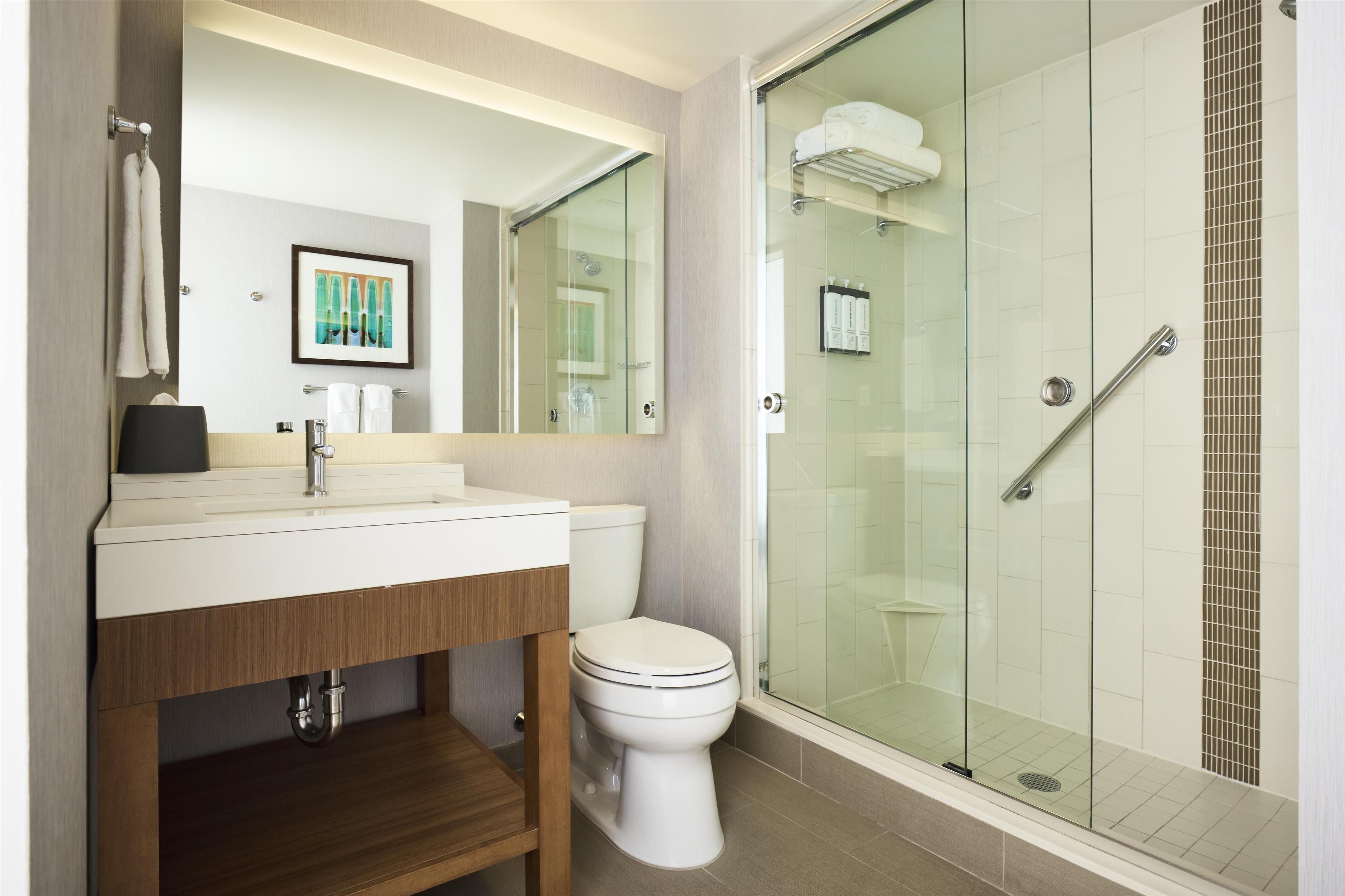 A modern bathroom with a glass-enclosed shower, a white sink, and a toilet.