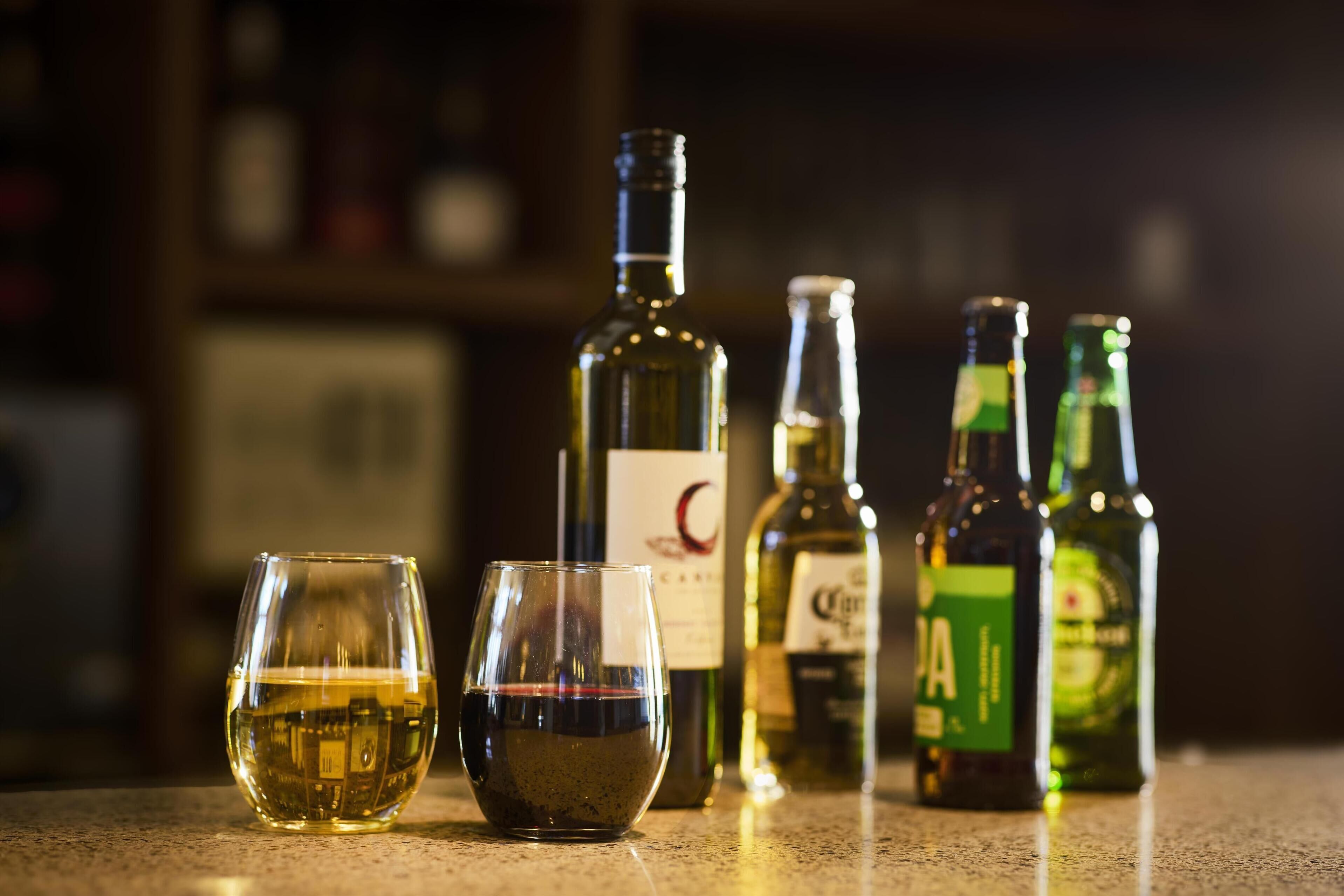 A glass of white wine and several bottles of wine on a countertop.