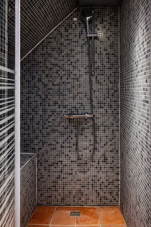 Une douche avec un mur carrelé et une pomme de douche en métal.