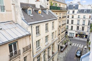 Un immeuble à plusieurs étages doté d’une cour intérieure, avec des balcons, une vue sur la rue et une voiture garée.