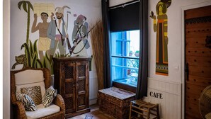 Um quarto acolhedor com um sofá de vime, um armário de madeira e uma janela grande com vista.