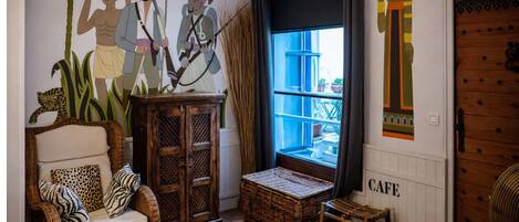 A cozy room with a wicker sofa, a wooden cabinet, and a large window with a view.