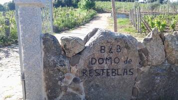 Eine Steinsäule mit der Aufschrift "B&B DOMO de RESTEBLAS" und ein Tor zu einem Weinberg.