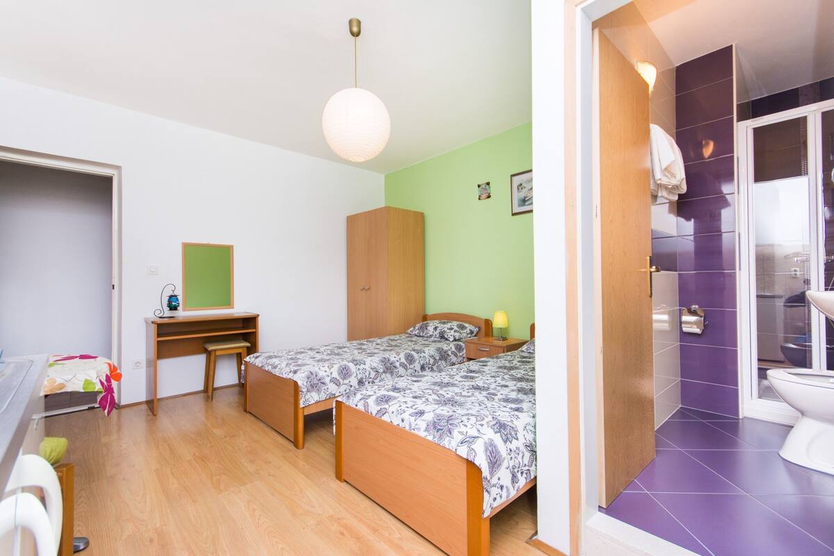 A bedroom with two single beds, a desk, and a wardrobe.