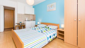 A bedroom with a bed, bedside tables, a wardrobe, and a kitchenette. - Nina Apartments (Konavle)