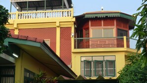 Ein mehrstöckiges Gebäude mit einem Balkon im oberen Geschoss und einer flachen Dachfläche im unteren Geschoss.
