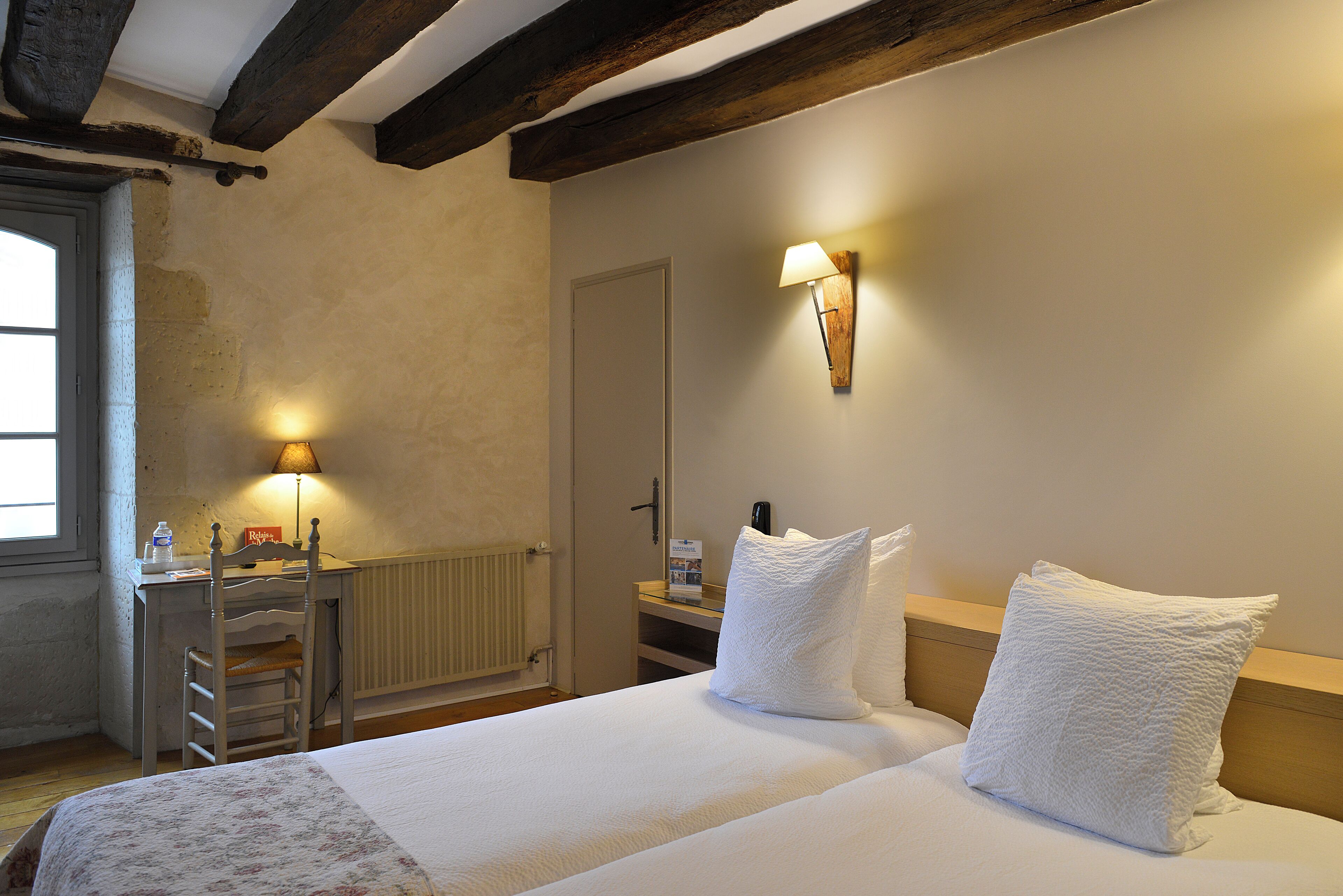 A bedroom with a bed, a desk, a chair, a radiator, and a wall-mounted lamp.