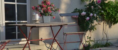 A patio with a table and chairs, a potted plant, and a wall-mounted bench.
